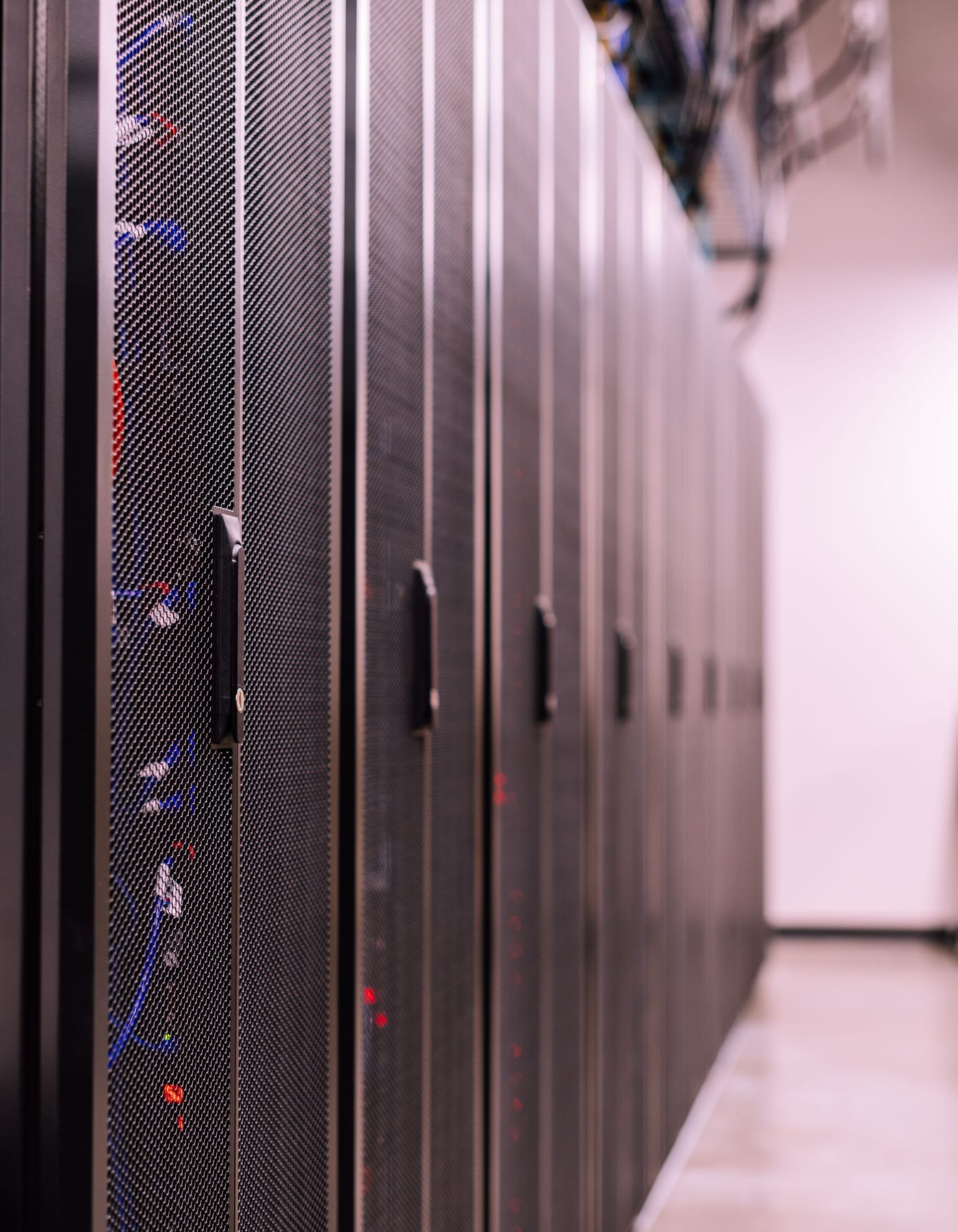 A row of mesh server cabinets in a datacenter aisle.